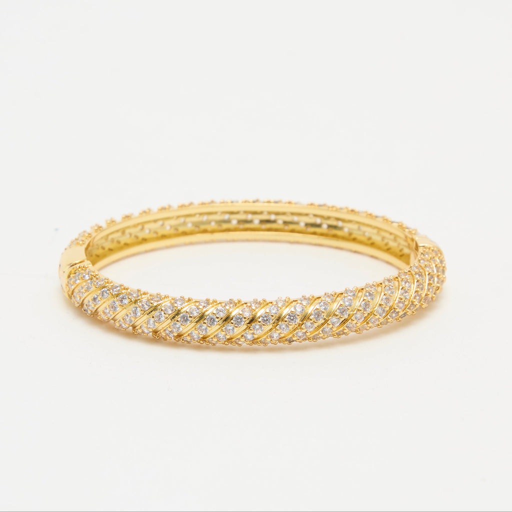 Gold bracelet with diamond accents on a light beige background
