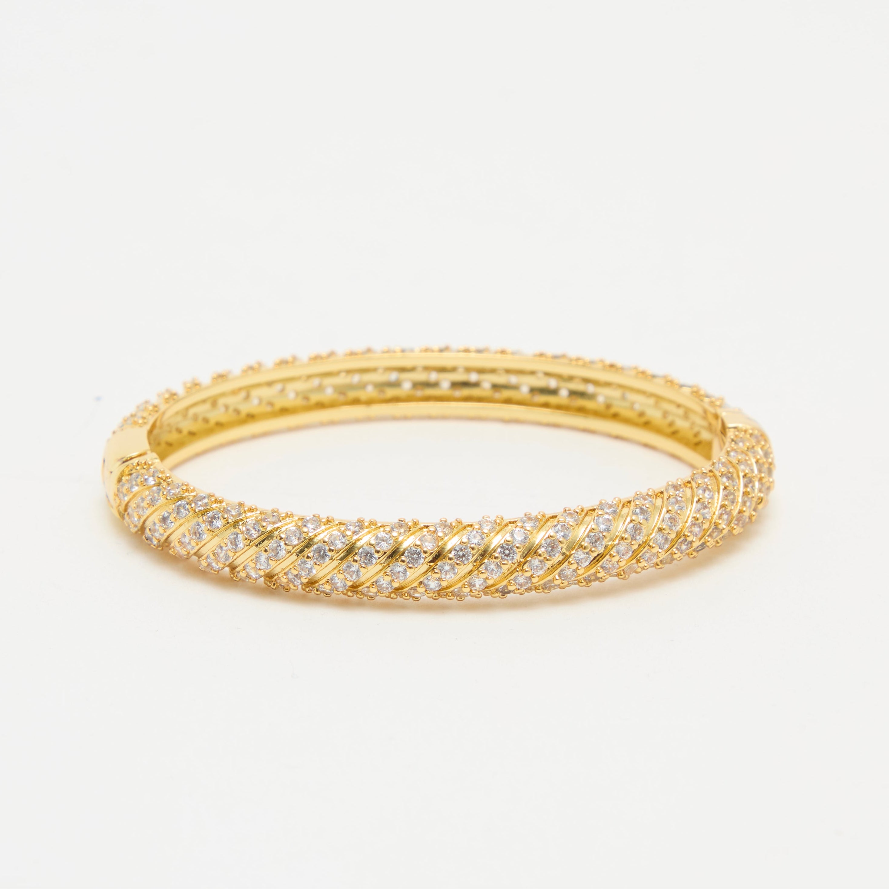 Gold bracelet with diamond accents on a light beige background