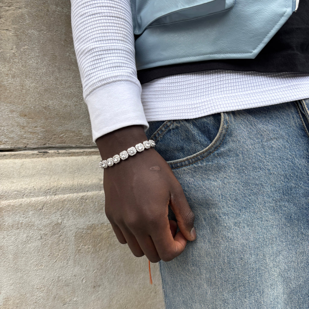 Person wearing a bracelet with a clear stone on a gray pavement.