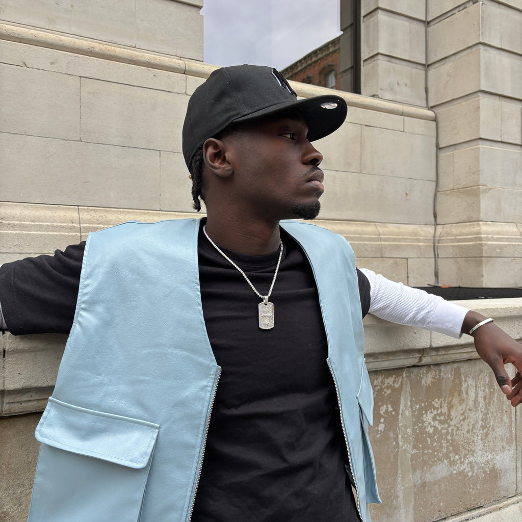 Person wearing a light blue jacket over a black shirt on a stone pavement.
