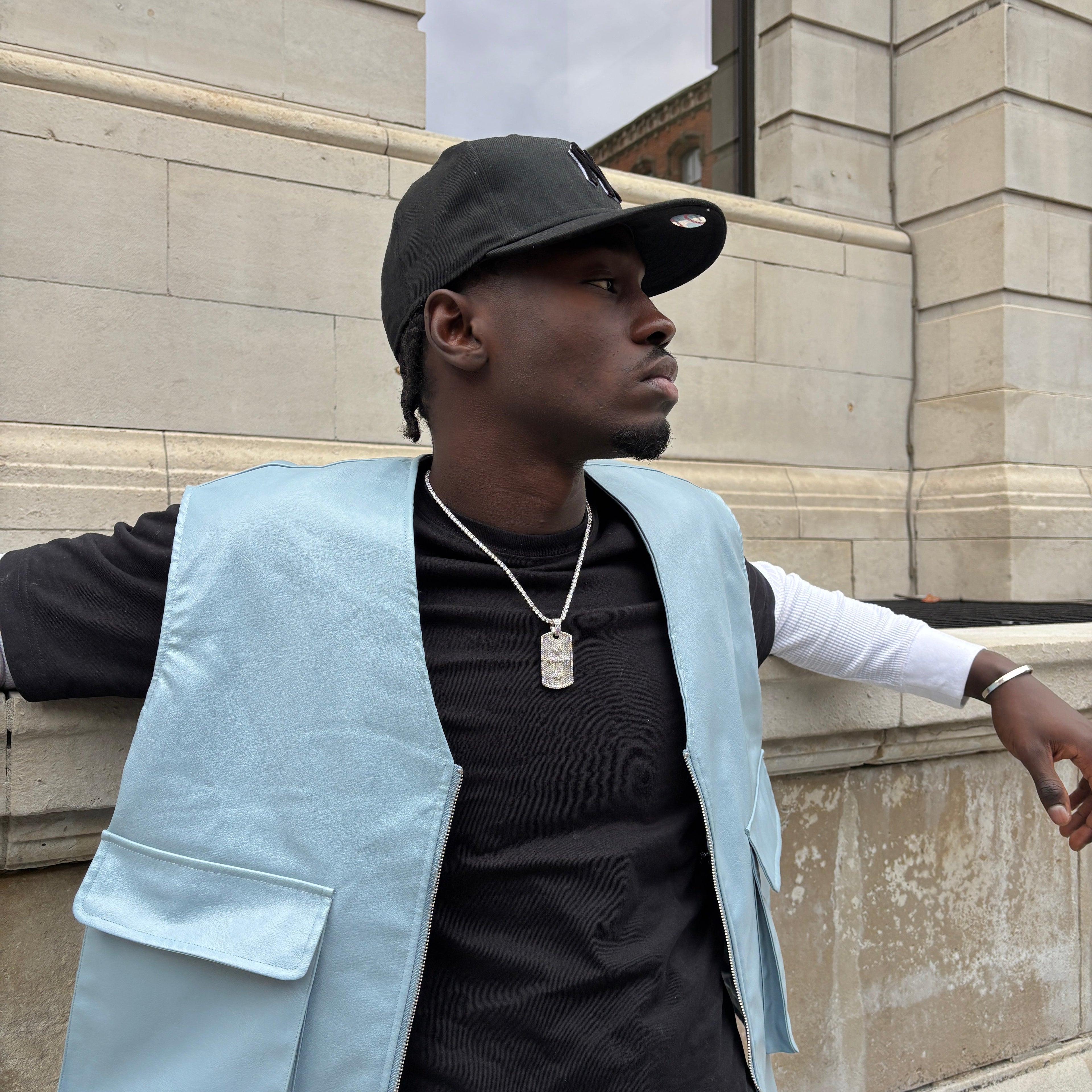 Person wearing a light blue jacket over a black shirt on a stone pavement.