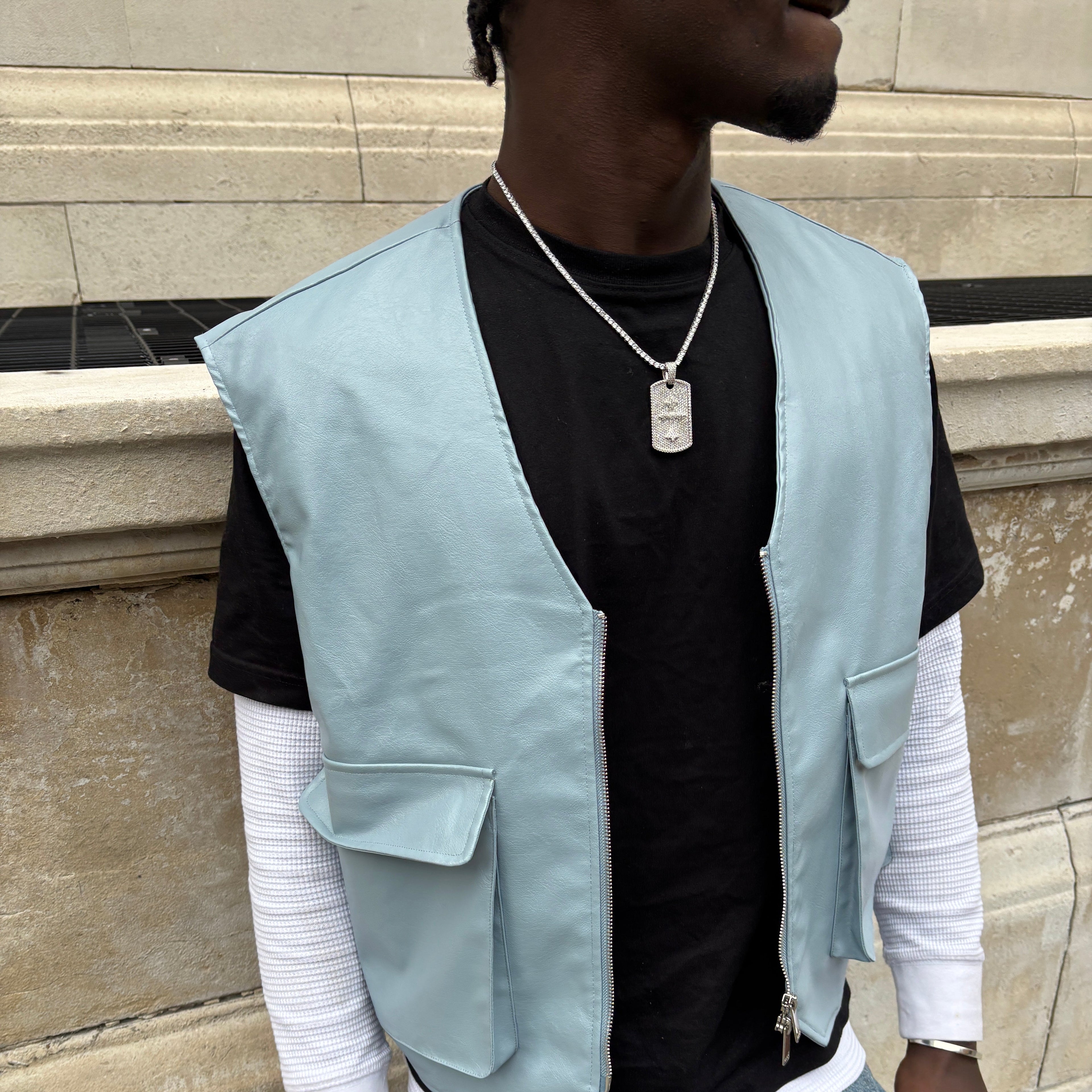 Person wearing a light blue jacket over a black shirt on a tiled floor.