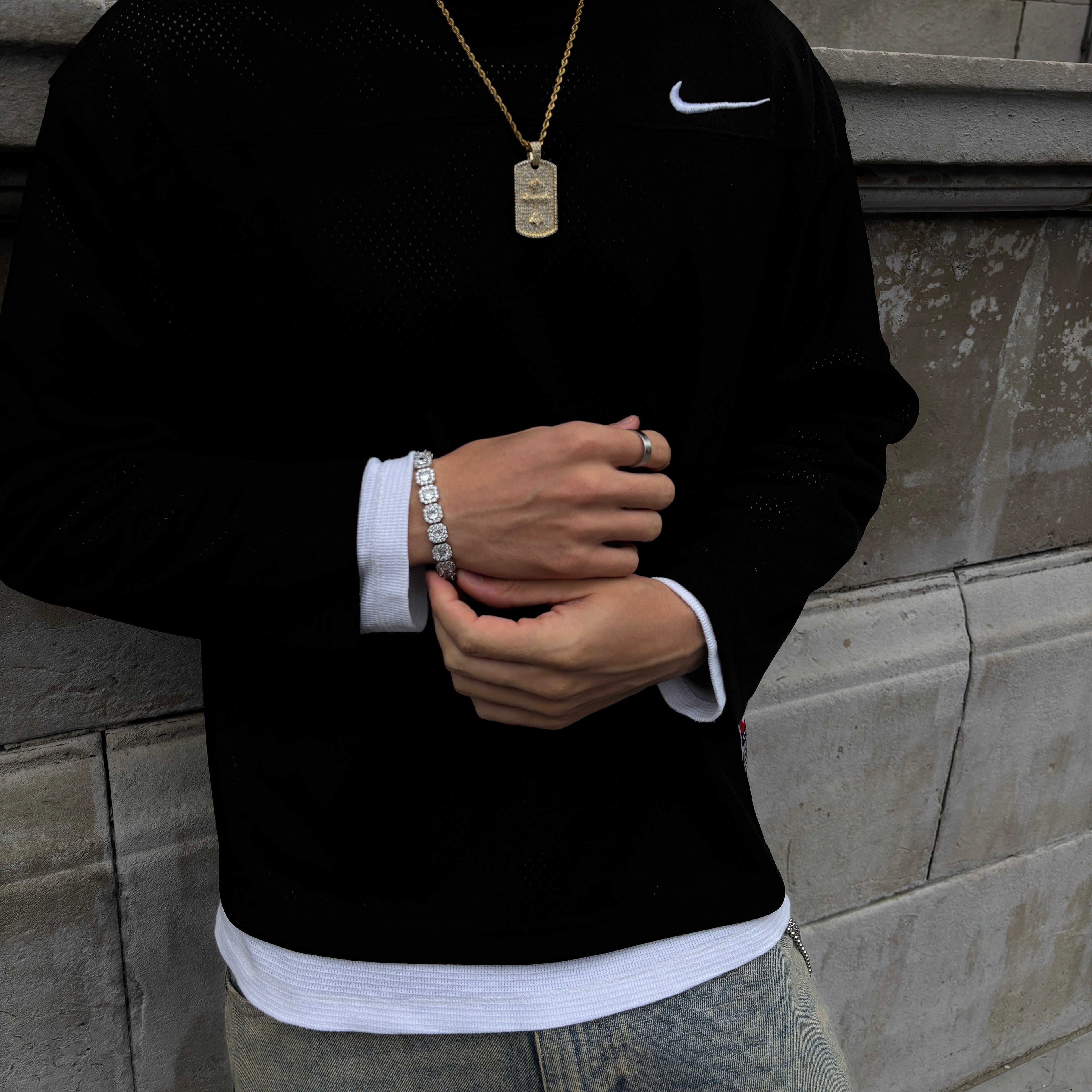 Person wearing a black suit with white trim, standing on a tiled floor. Silver bracelet 