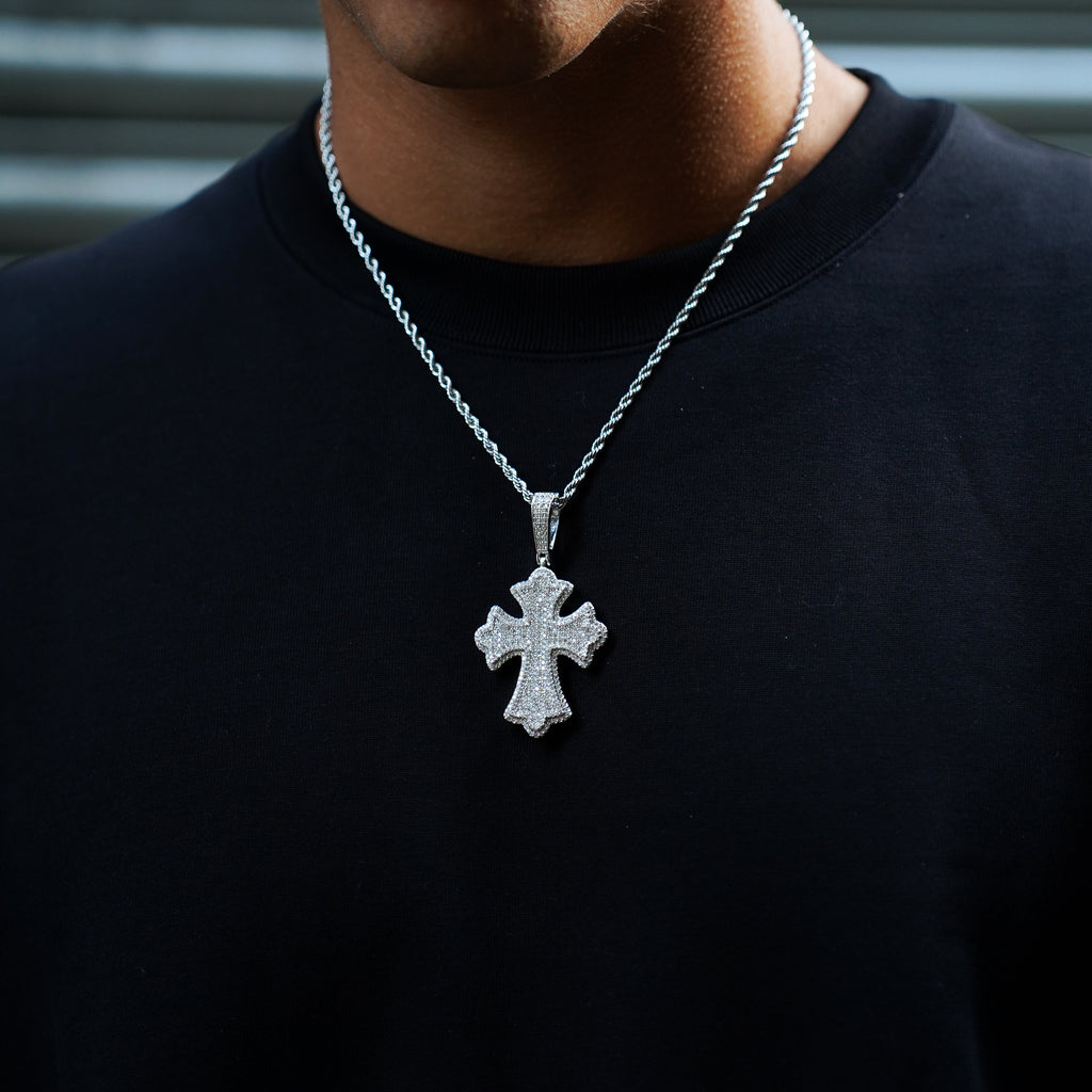Person wearing a black shirt with a silver cross pendant necklace.