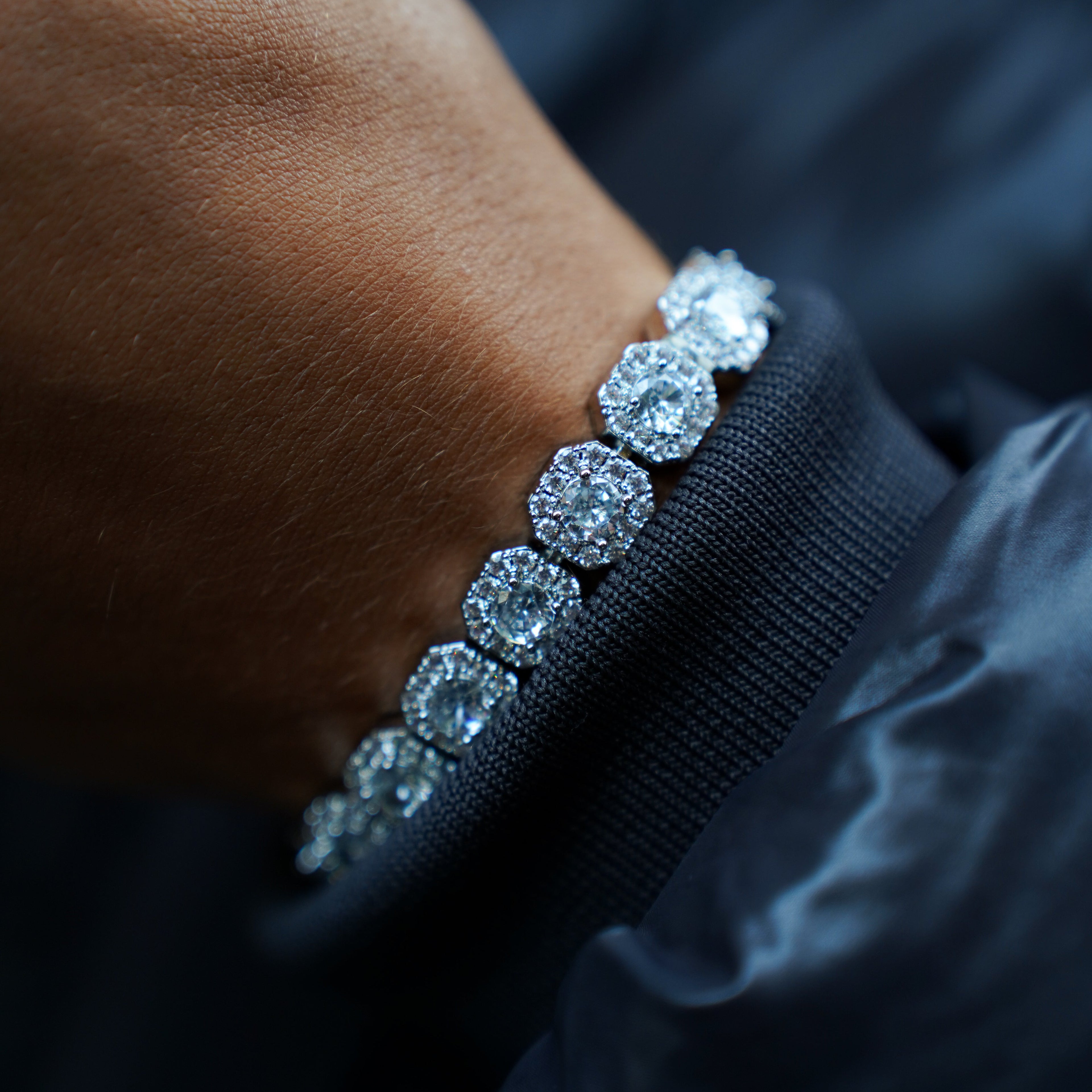 Close-up of a hand wearing a diamond bracelet with a dark background