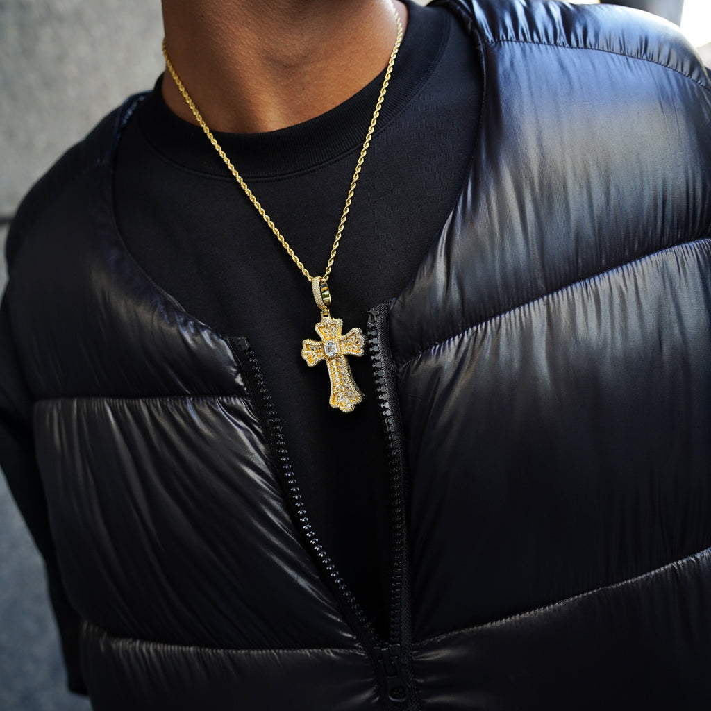Person wearing a black puffer jacket with a gold necklace featuring a cross pendant.
