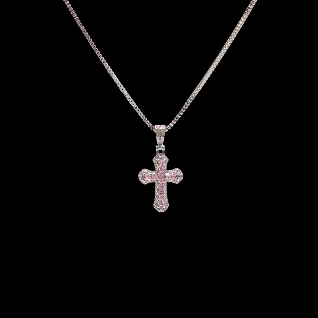 Cross-shaped pendant with pink stones on a chain against a black background