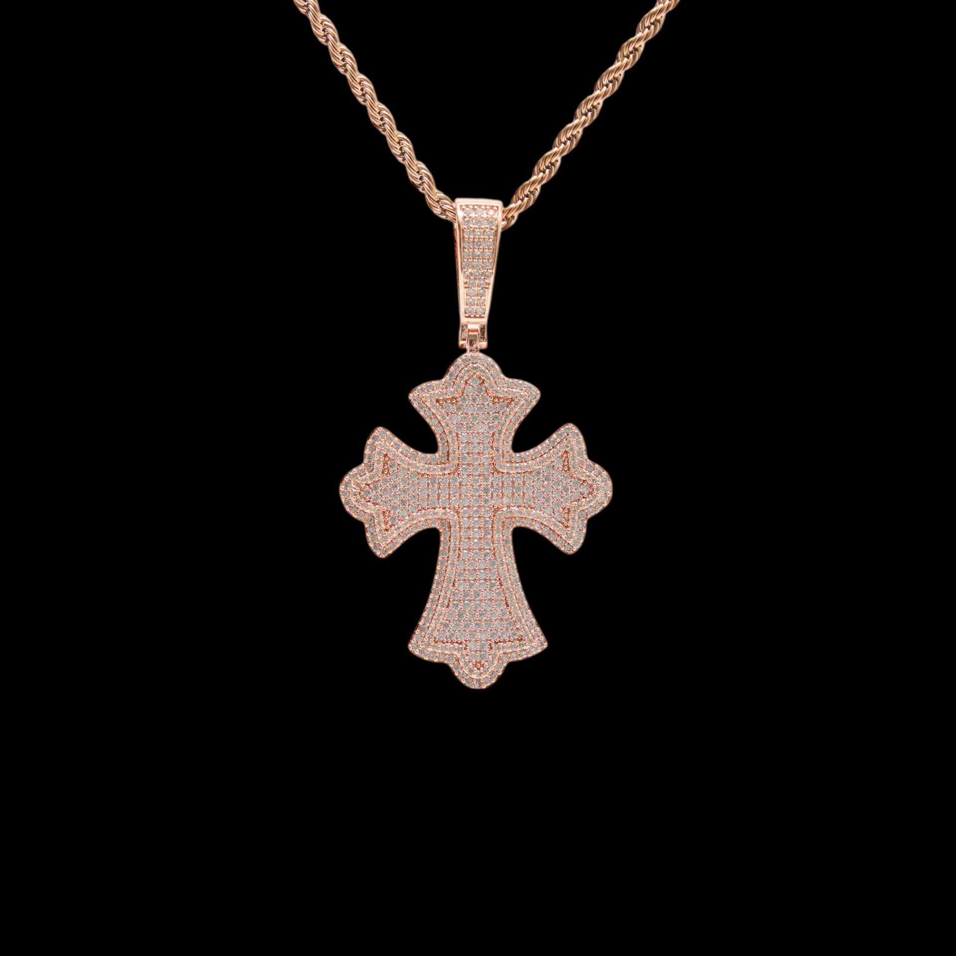 Rose gold cross pendant on a chain against a black background